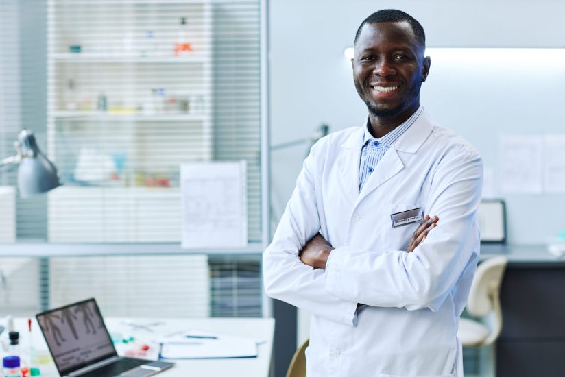Waist up portrait of smiling black man standing in medical laboratory, copy space